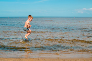 boy swimming in the sea, jumping in the waves of the ocean on the beach