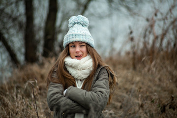 Emotion photo. Cute white emotional caucasian teen girl in a blue hat stands in the park in cold autumn weather.