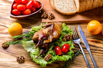 Serving board with whole baked quails in a rustic wooden setting