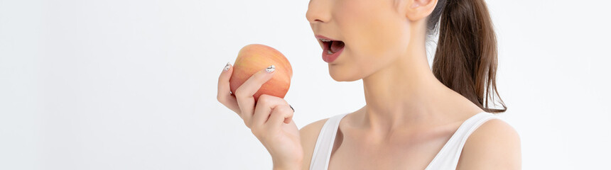 Close up of Portrait of young woman eating red apple isolated over white banner background with copy space for Healthy food. Healthy food concept. Skin care and beauty..Banner panorama.