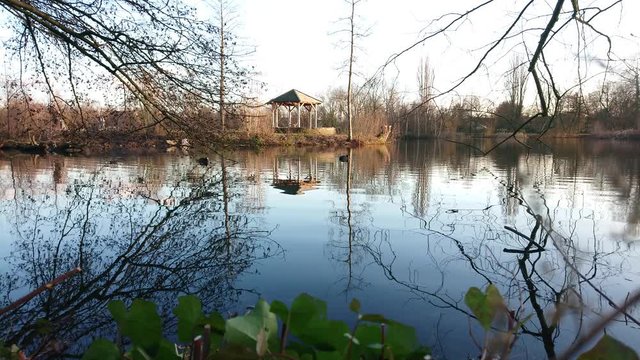 Booth near lake water with tree branches on foreground.