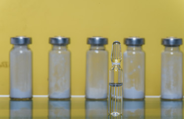 Glass medical ampoule vial for injection. Medicine is liquid sodium chloride with of aqueous solution in ampulla. Close up. Bottles ampule multicolor on background color and water. Human plasma.