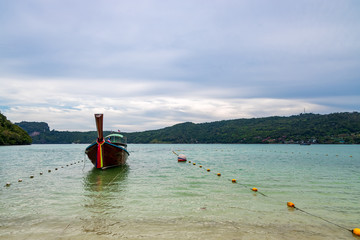 traditional wooden longtail boats parked at a beach in Phi Phi Island. Clear water and clean beach.