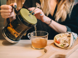 Gyro with tea at wooden desk in cafe. Hands