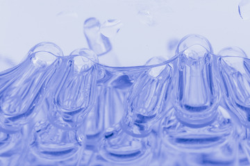 Glass medical ampoule vial for injection. Medicine is liquid sodium chloride with of aqueous solution in ampulla. Close up. Bottles ampule multicolor on background color and water. Human plasma.