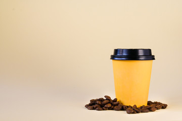 yellow paper cup with coffee grains on a yellow background
