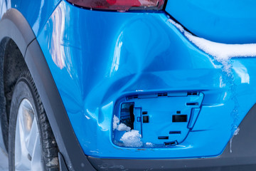 Dented rear bumper of a modern hatchback with the snow remains