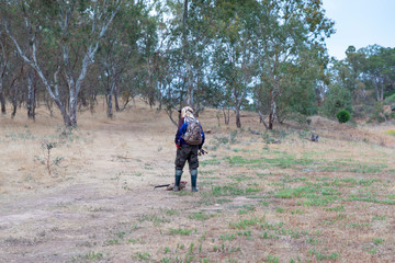 Fototapeta premium A fisherman walking through dry bushland towards a fresh water reservoir to locate a suitable fishing spot