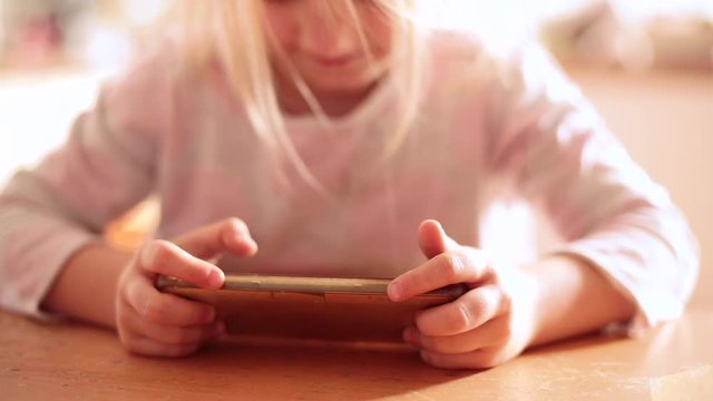Young child girl using smartphone watching video and playing games. Addiction danger concept.