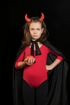 Foto de estudio de una niña con un disfraz de diablo. Fondo negro