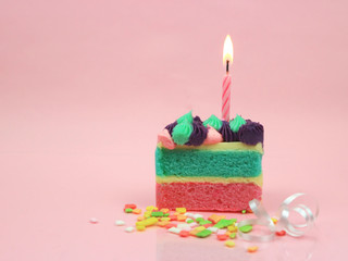 Happy birthday cake and bow candle on pink background with copy space.