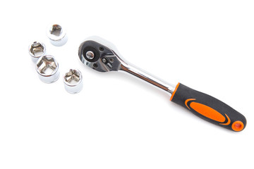 Ratchet wrench with black and orange handles with set of heads for it, isolated over a white background. Tools and hardware for everyday. Construction and repair. Copy space. Selective focus