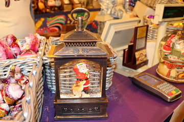 Christmas decorative lantern with Santa Claus inside on the store counter on the background of other toys and the Bank terminal.