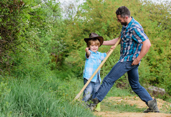 Naklejka na ściany i meble Little boy and father in nature background. Spirit of adventures. Little helper in garden. Child having fun cowboy dad. Farm family. Holidays at parents farm. Growing cute cowboy. Weekend at farm