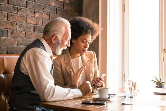 An Older Executive Presenting Business Data Over The Phone To The Business Owner.