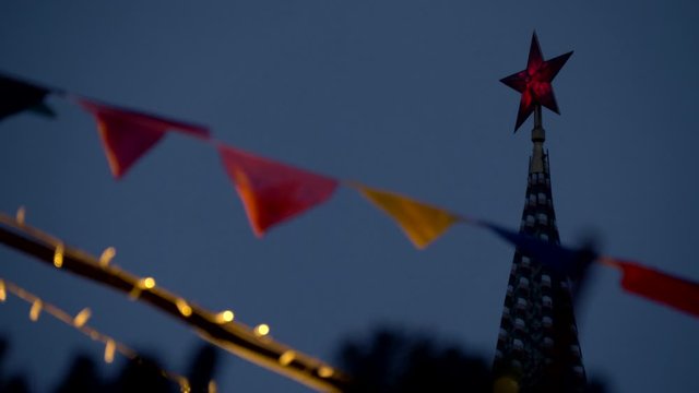 Kremlin, red star. The Moscow Kremlin and the red square on which stands the Spasskaya tower with a golden clock and a bright red star on top. Closeup. New Year's Fair, garlands,decorations and flags.