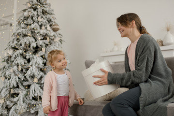 Family Christmas morning in a bright minimalistic living room near the Christmas tree.