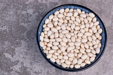 White beans in a bowl on a structured grey background