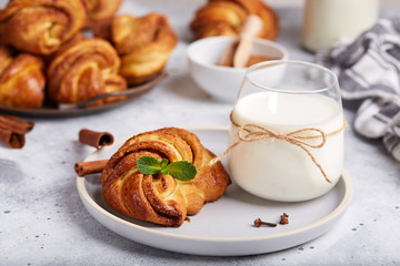 Buns from yeast dough with brown sugar and cinnamon. Delicious homemade dessert served with a glass of milk. 