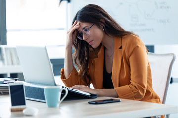 Business young woman with headache working with laptop in the office.