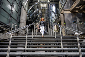 Close up portrait of a trendy young woman coming out from a business building in the business district of London, England