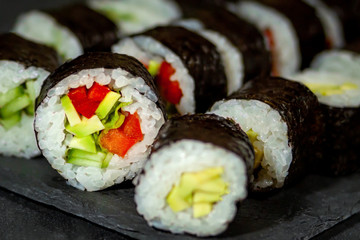 vegetarian sushi rolls with avocado sweet pepper on a black board close-up