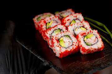 sushi rolls with green onion near on a black board close-up