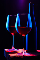 Two glasses of red wine with bottle on wooden table and dark background. Intimate atmosphere. Romance concept