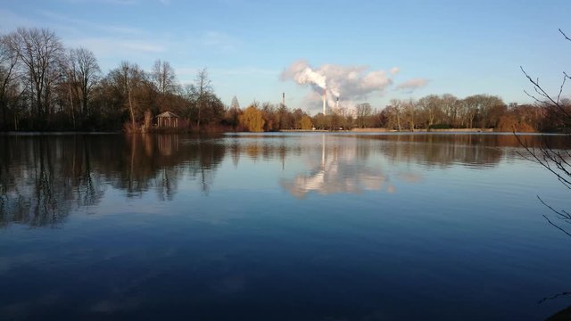 Timelapse of the lake with smoke from factory chimney at background.