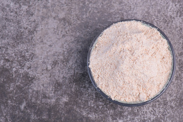 Flour in a bowl on a grey structured background