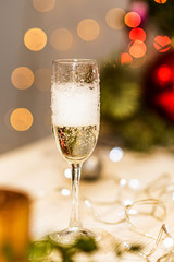 A glass of champagne on the background of New Year's blurry lights. Bubbles of sparkling wine in a glass.