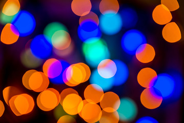 Christmas colorful bright background. Festive abstract bokeh, defocused large colored lights garland orange and blue on a black background. Copy space