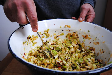 Man preparing leek salad with dried chile peppers in a large bowl