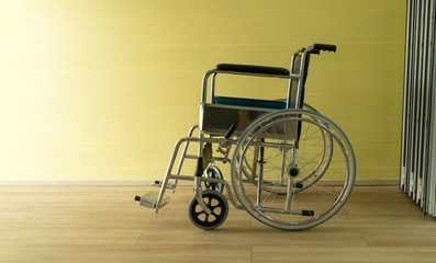 Wheelchair is parked in a room with a yellow wall in a depressed atmosphere.