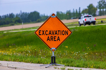 A close up of a motorist beware warning sign near a roadside excavation area, with blurred truck and grass verge in the background with copy space