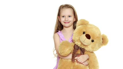 Beautiful little girl 5-6 years.She is holding a large teddy bea