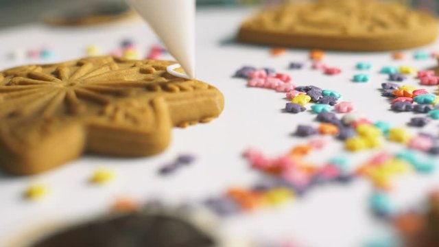 Putting sweet white cream on differents gingerbread cookies. Sweet Christmas holiday cookies with cream. Cooking yummy sweets in the bakery. 4k close up. Slow motion footage. Decoration of cookies.