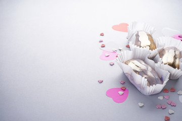 Eclairs with confetti in the form of hearts on a gray background, flat lay with place for text. French dessert.
