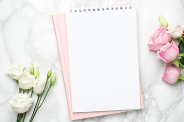 Beautiful white and pink roses flower and notebook on marble background