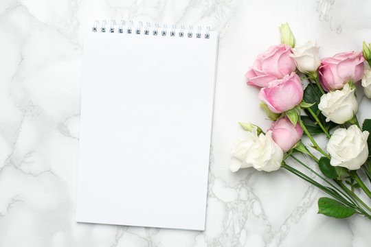 Beautiful white and pink roses flower and notebook on marble background