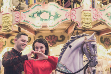 Obraz na płótnie Canvas romantic couple taking a moment to kiss while riding horses on carousel
