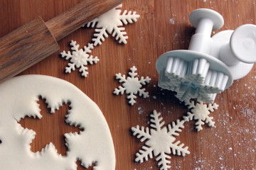 Flat lay snowflakes made from sugar paste on wooden board with rolling pin, plunger or cutter mold, sugarcraft fondant, cake decorating. Selective focus.