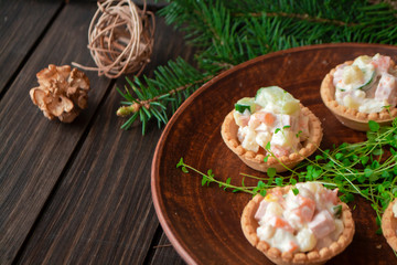 Fototapeta na wymiar Russian traditional olivier salad in tartlets with potatoes, cucumber, egg, mushrooms and mayonnaise