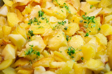 Fried potatoes in an iron pan, yellow texture close up