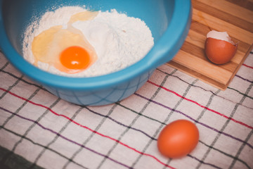 Vintage look on bowl with flour and raw egg ready for mixing and baking.