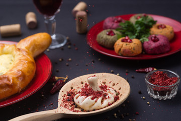 Georgian food on black table. khinkali, phali,  khachapuri with tomatos, adjika and a glass of wine.