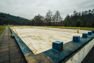Old empty outdoor swimming pool during autumn.