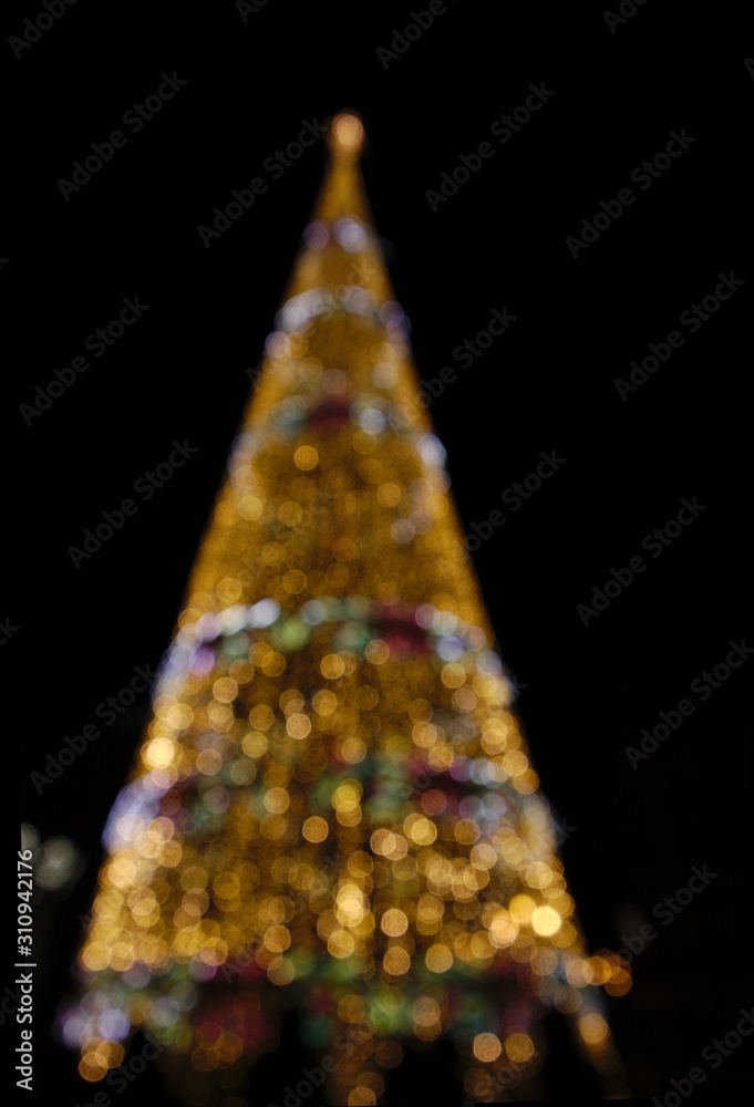 Wall mural Silhouette of a Christmas tree illuminated with blurred lights