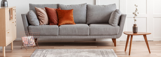 Autumn colored pillows on grey sofa in modern living room interior