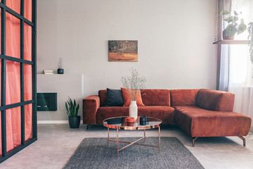 Real photo of a simple, elegant living room interior with red furniture and an oil painting on...